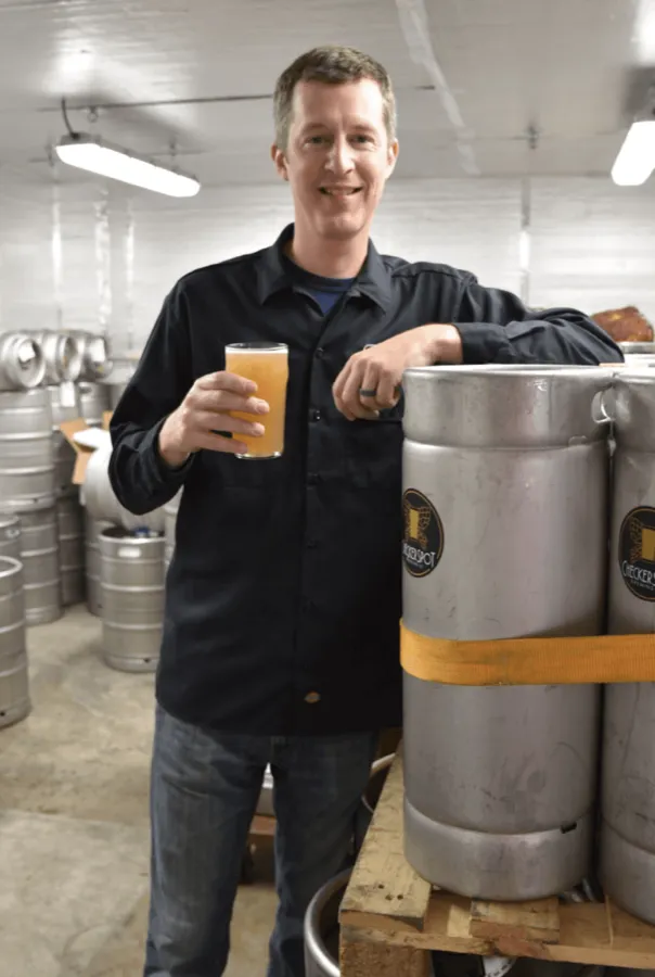 Rob Neff with a fresh pour beside Checkerspot kegs