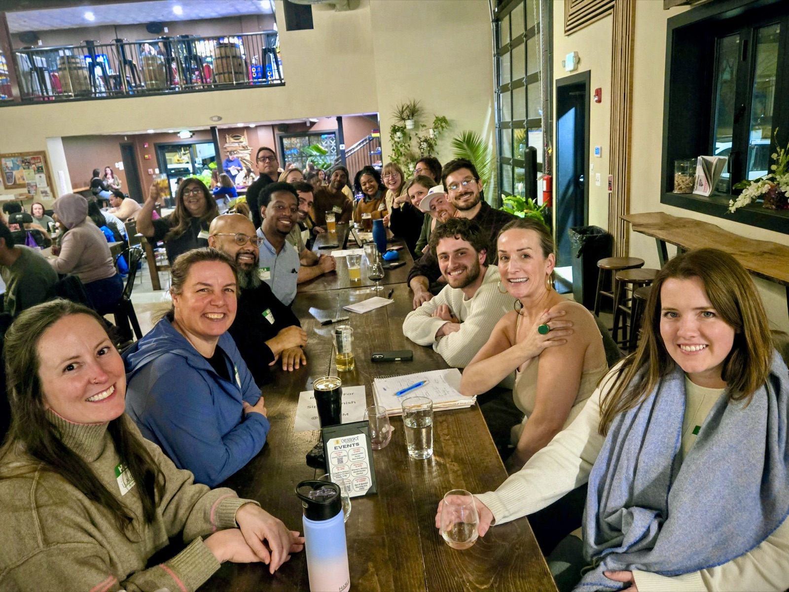 A large group gathered around a long table in the taproom