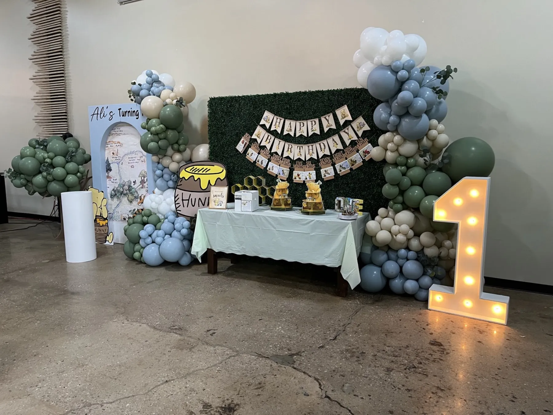 A woodland-themed birthday display with balloons and a marquee number one